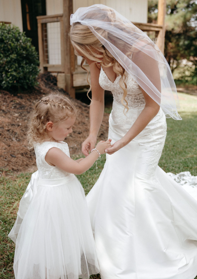 Bride giving bracelet gift to little girl on wedding day